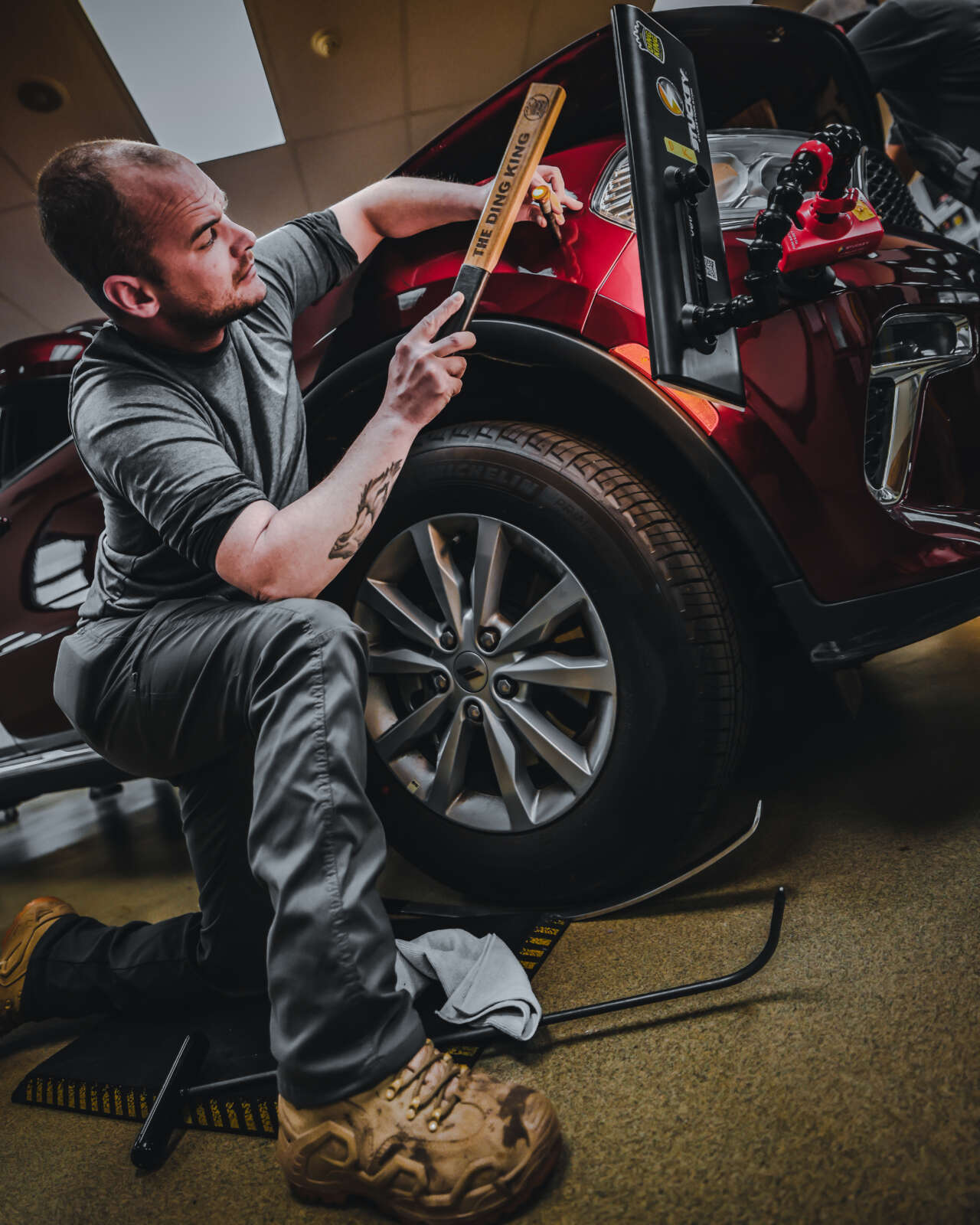 A technician receiving advanced PDR training while working on a car in a garage.