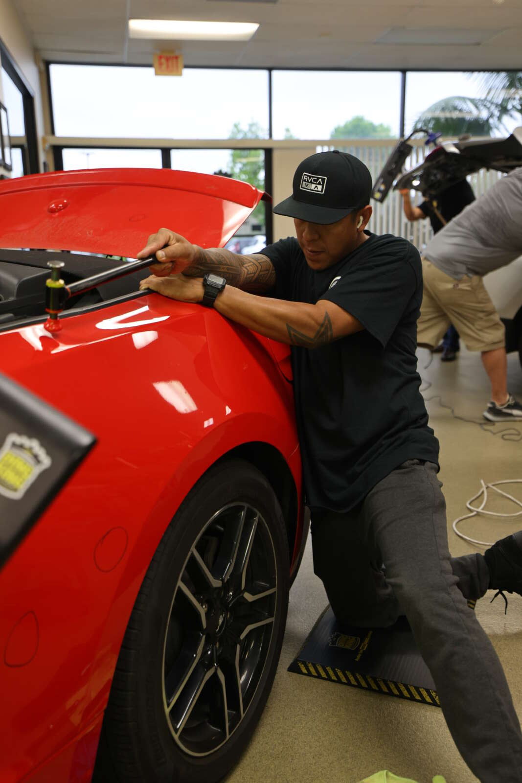 A man undergoing Advanced PDR Training while working on a red car.