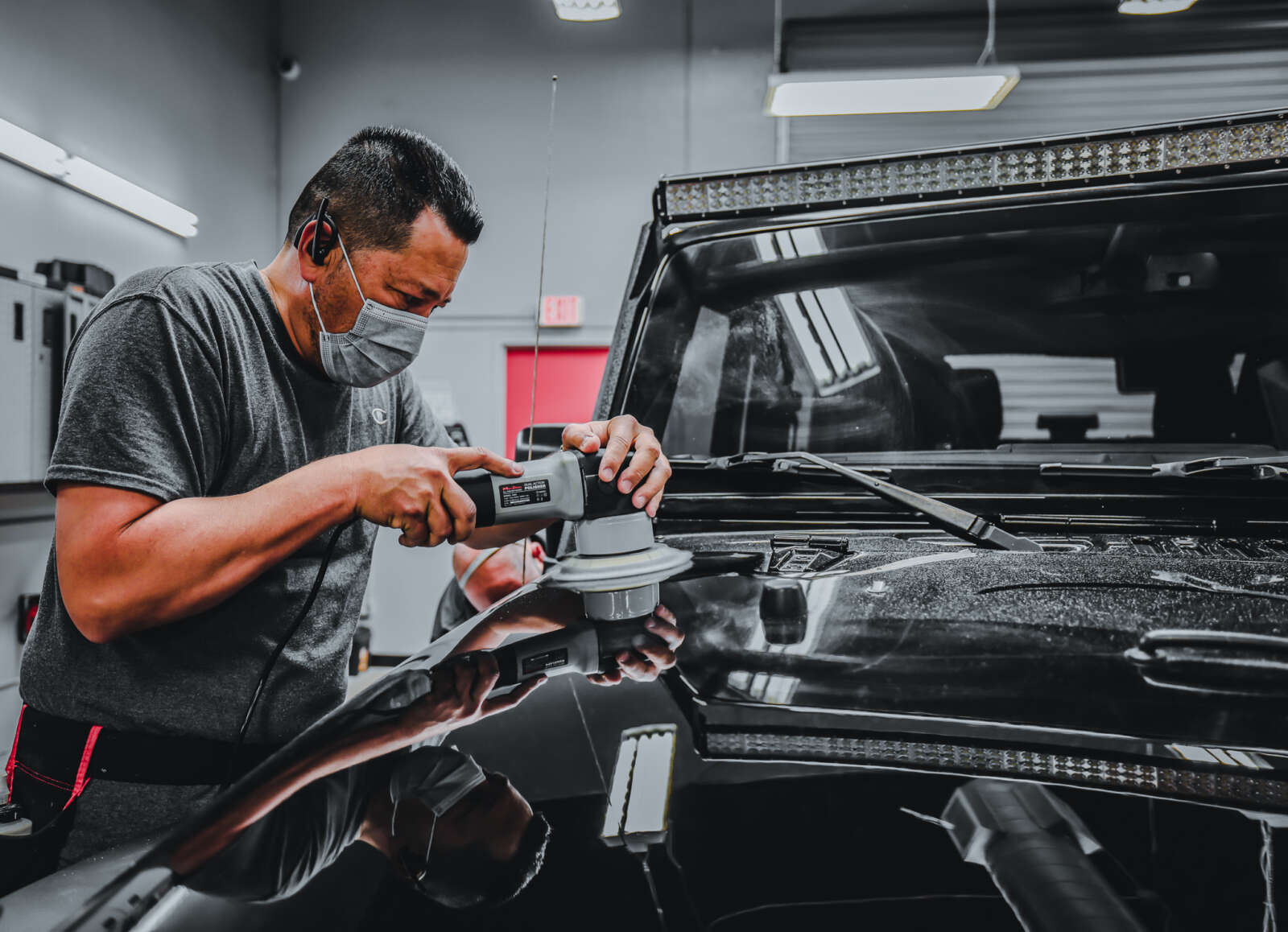 A man receiving paint correction training on a black jeep hood.