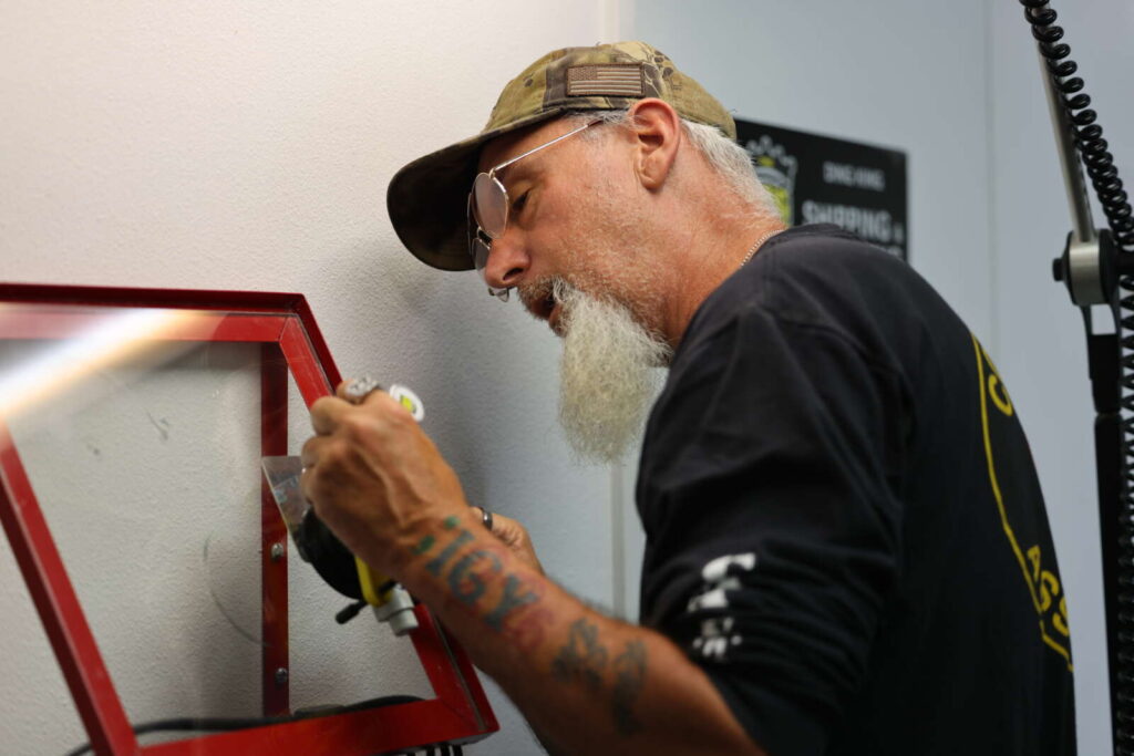 A man with a beard learning how to perform windshield repair.