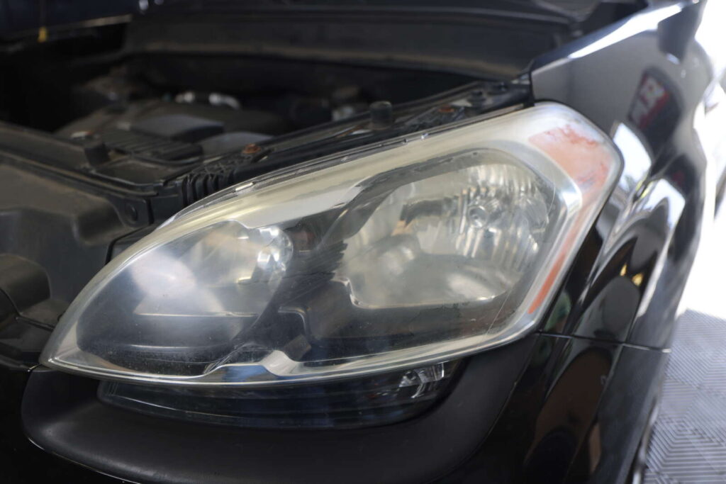 A black car with its headlights being renewed.