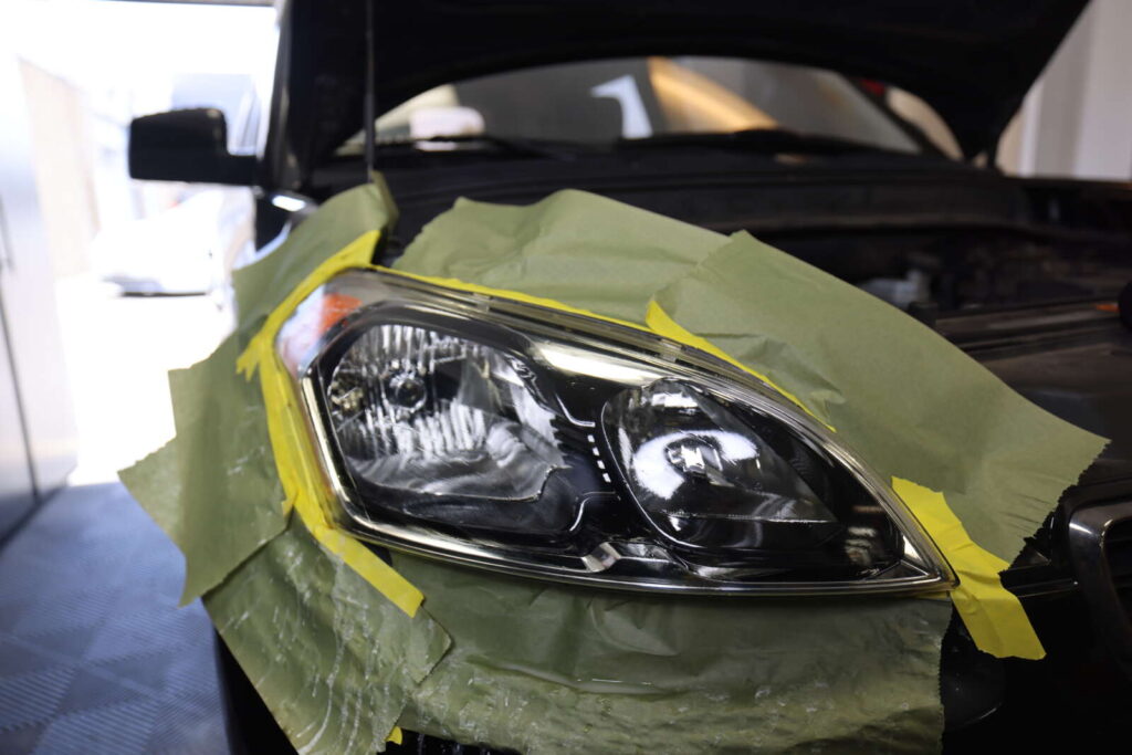 The car's headlight undergoes renewal with tape.