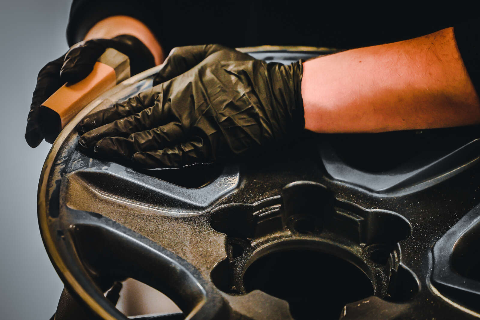 A person is sanding a rim as part of their paintless dent repair training.